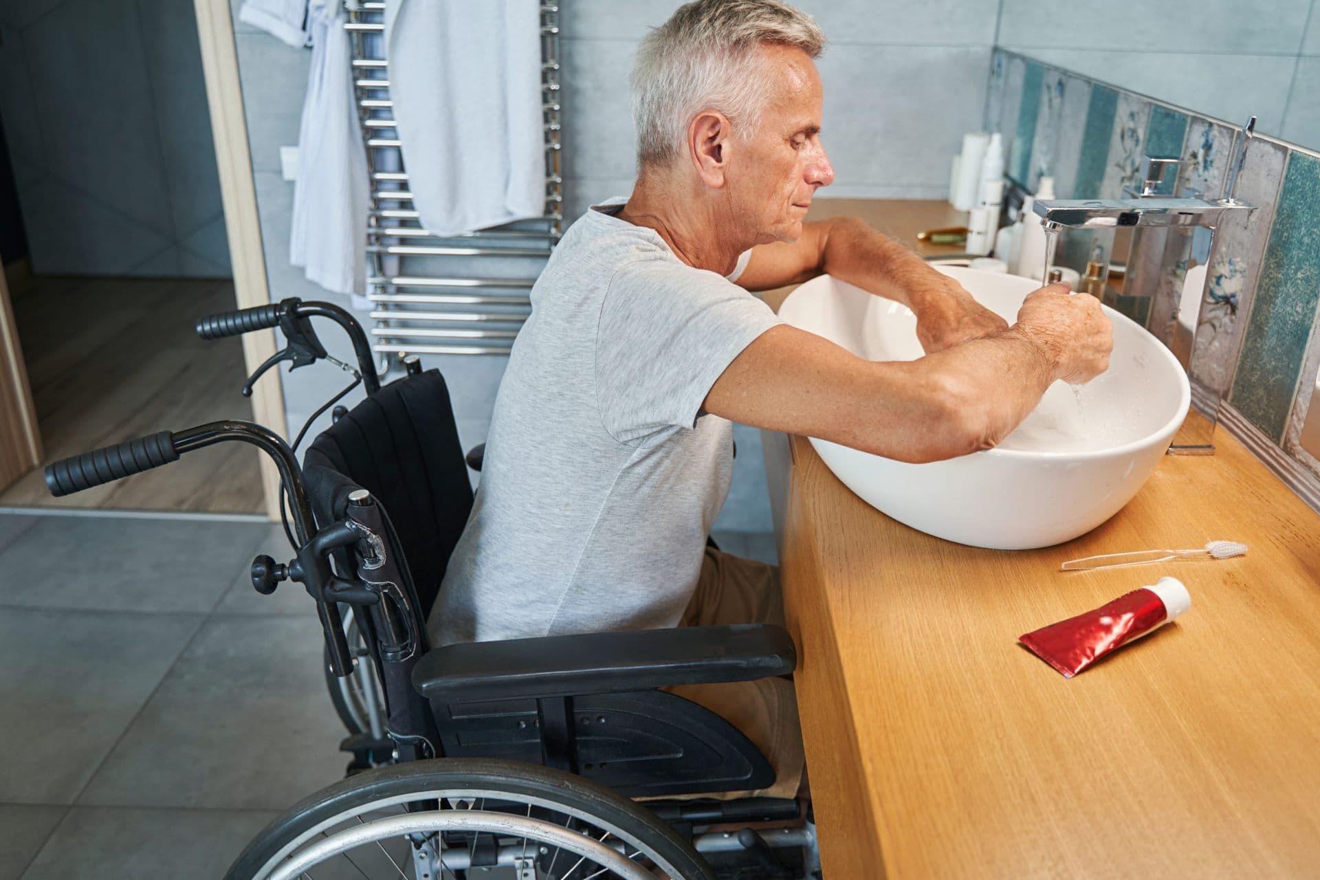 bigstock-Aged-Man-With-Physical-Disability-cleaning-hands-in-sink-scaled